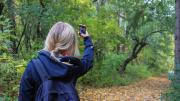 Niña haciendo fotos en la naturaleza con teléfono móvil