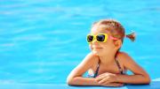 Niña sonriente apoyada en el borde de la piscina