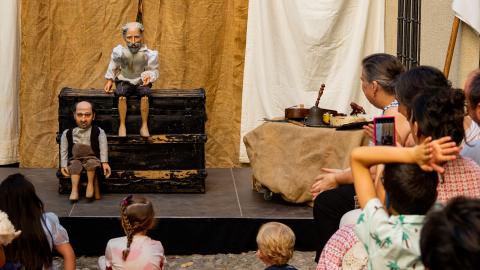 Marionetas en escenario y público familiar observándolas