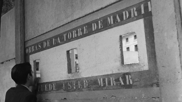Obras en la Torre de Madrid, 1955. Juan Miguel Pando Barrero. Fototeca IPCE Imagen de un hombre de espaldas mirando a través de unos agujeros en una fachada