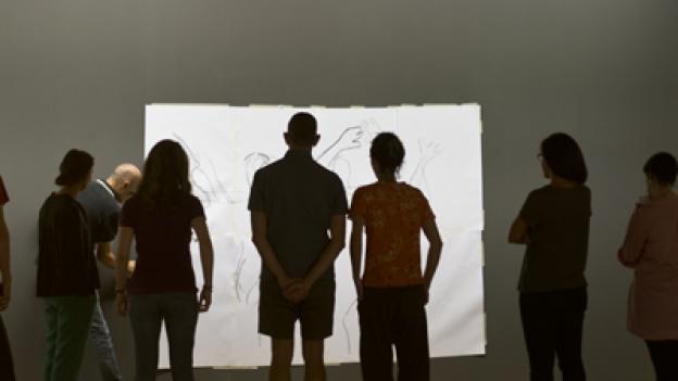 Grupo de gente joven observando un lienzo en blanco en una sala de exposiciones