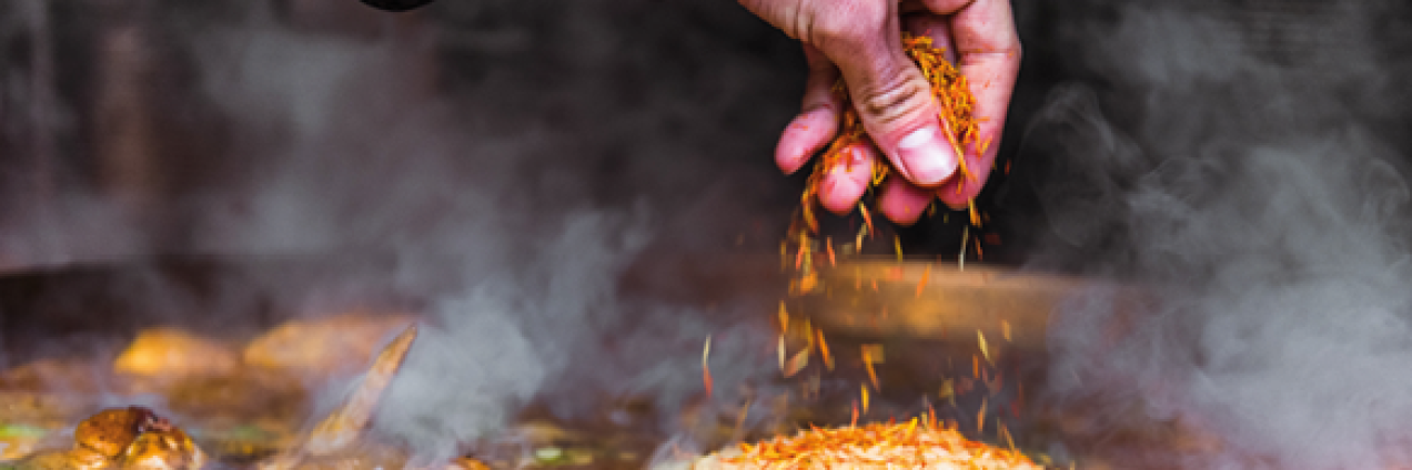 persona echando el arroz a la paella