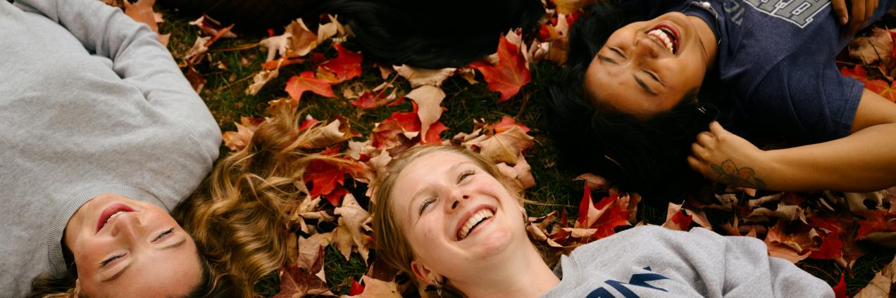 Adolescentes tumbados sobre hojas de otoño