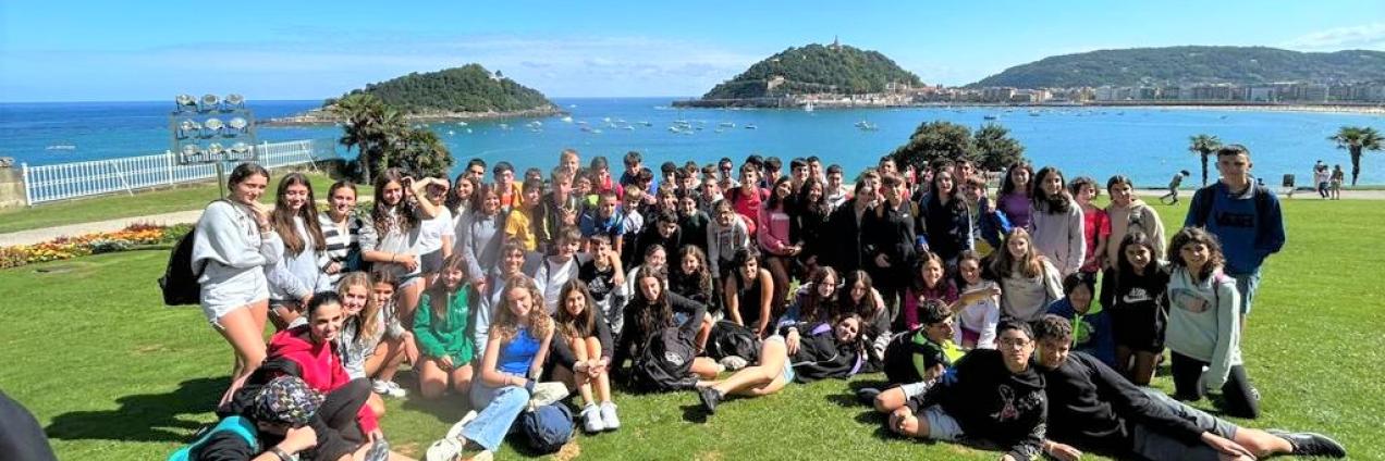 Grupo de jóvenes en el cesped con el mar de fondo