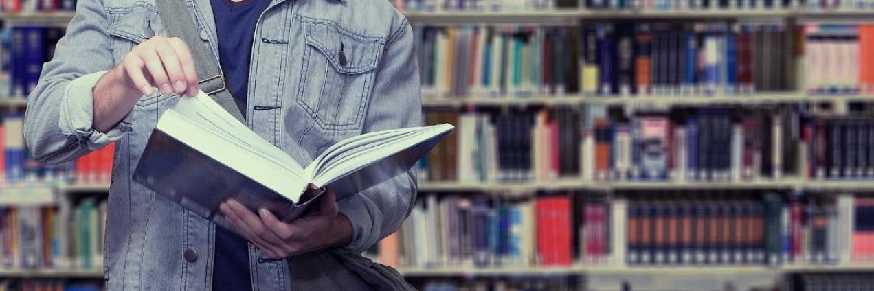Persona en una biblioteca sosteniendo un libro