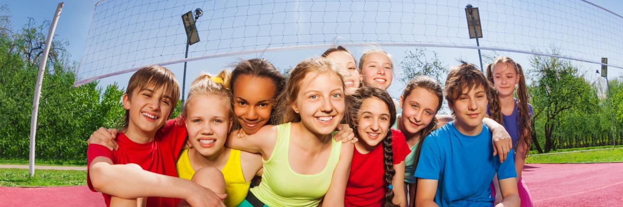 Niños sonrientes sentados en una cancha de voleibol