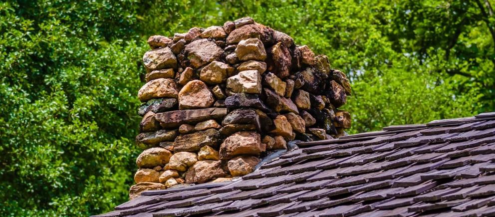 Chimenea de piedra en lo alto de un tejado de pizarra