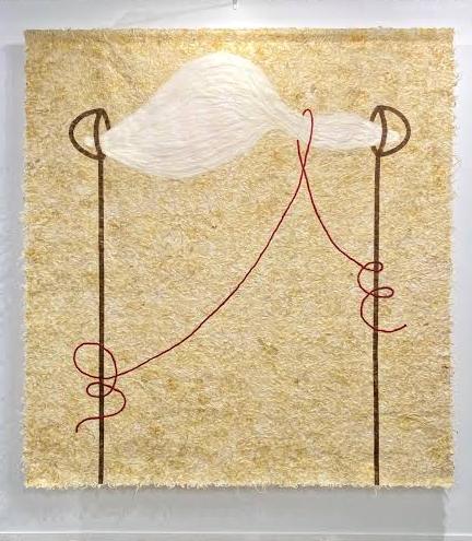 Lienzo de lana colgado en una pared. Esta bordado con hilos rojos y lleva la aplicación en lana de una gran nube blanca