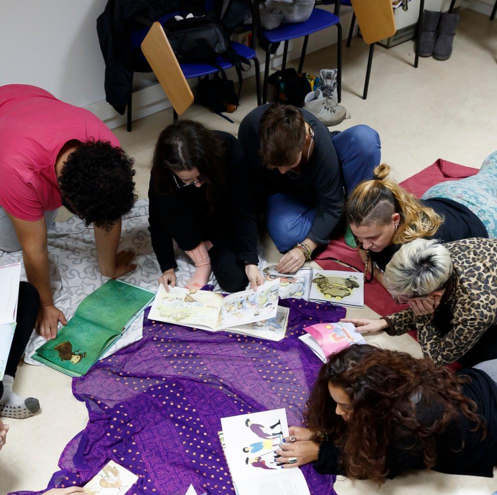 Grupo de jóvenes en el suelo leyendo libros