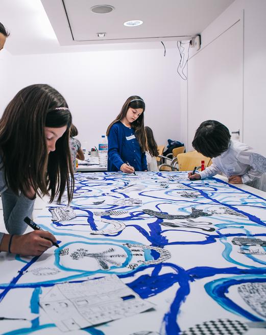 Niños pintando con pinceles líneas curvas en distintos tonos de azul