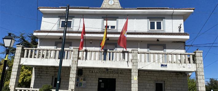 Fachada delantera con banderas del edificio del Ayuntamiento de Pedrezuela