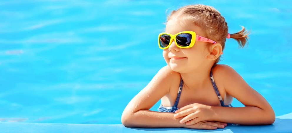 Niña sonriente apoyada en el borde de la piscina