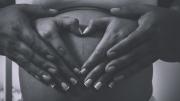 Una pareja con las manos enlazadas sobre el vientre de la mujer embarazada