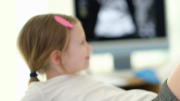 niña en consulta tumbada con pierna doblada mientras la examina la médica