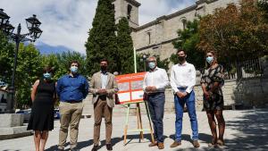 El consejero junto el alcalde de la localidad y otros asistentes posando delante de la iglesia con el cartel de las obras