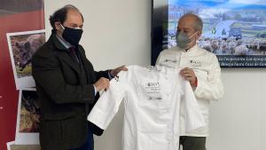 El viceconsejero junto al cocinero sujetando una chaquetilla de chef