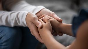 Las manos de una persona mayor tomando las de un niño