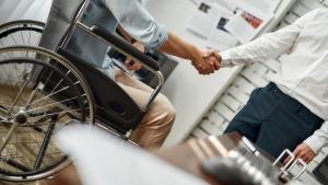 Una persona en silla de ruedas da la mano a otra que le ha contratado 