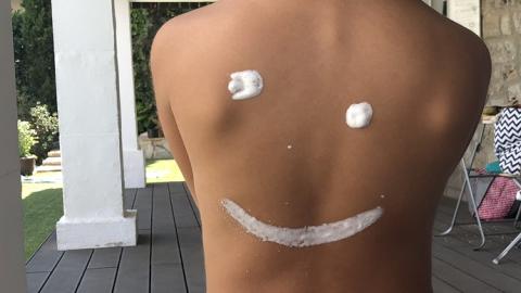Espalda con crema haciendo el dibujo de una sonrisa