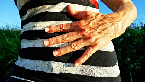 imagen del abdomen de una persona con una mano indicando dolor