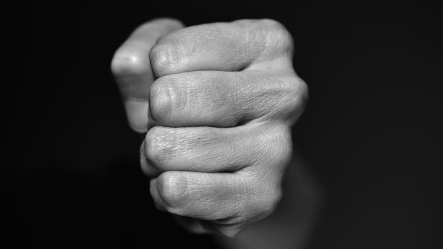 puño de la mano saliendo de la oscuridad