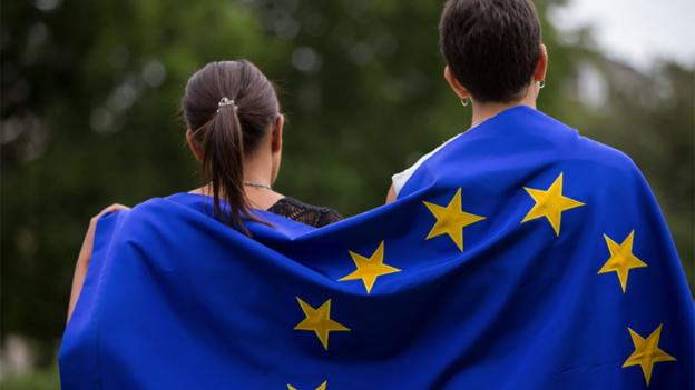 Dos jóvenes con una bandera de la UE en sus espaldas