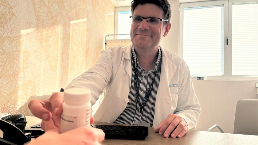 Doctor entrega frasco de pastillas a un paciente