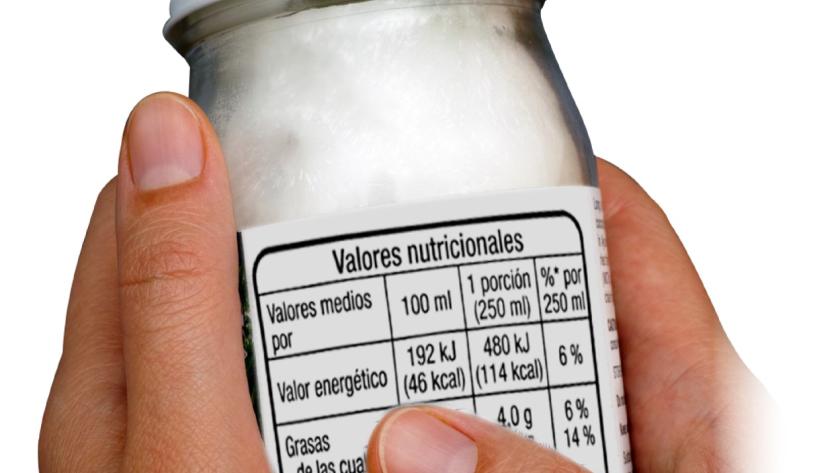 Manos con un yoghurt etiquetado con la información nutricional