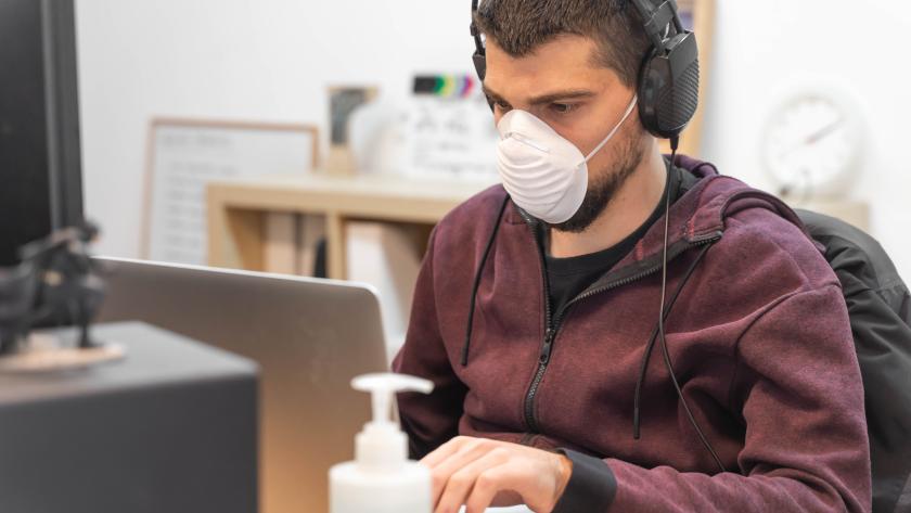 Una persona con mascarilla frente al ordenador