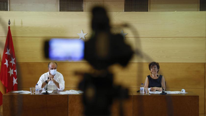 Plano general de los dos representantes de sanidad encargados de dar la rueda de prensa sentados en una mesa frente a los micrófonos
