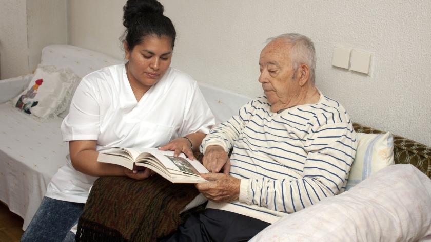 Hombre mayor y mujer cuidadora sentados