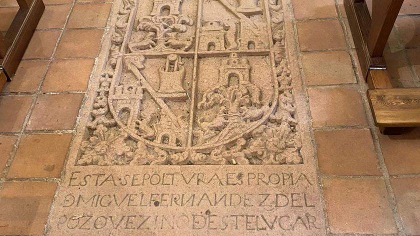 lápida en piedra sobre el suelo, presenta un escudo cuartelado y una inscripción