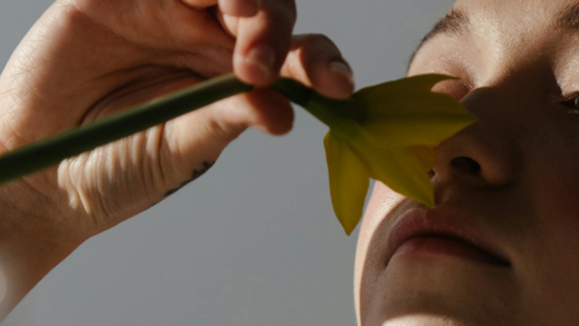 Imagen de una pernosa oliendo una flor