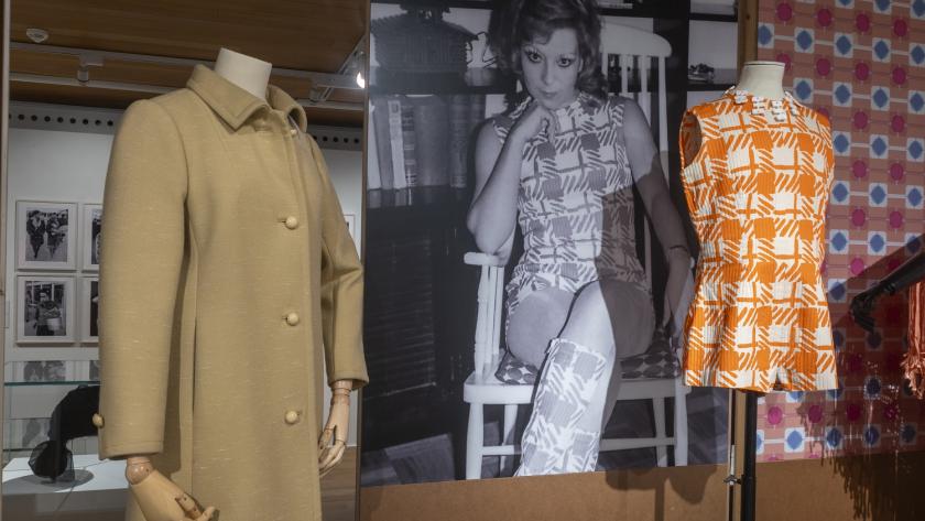 Detalle de dos piezas de indumentaria acompañadas de una fotografía en blanco y negro en la que se aprecia una mujer con una de las piezas expuestas
