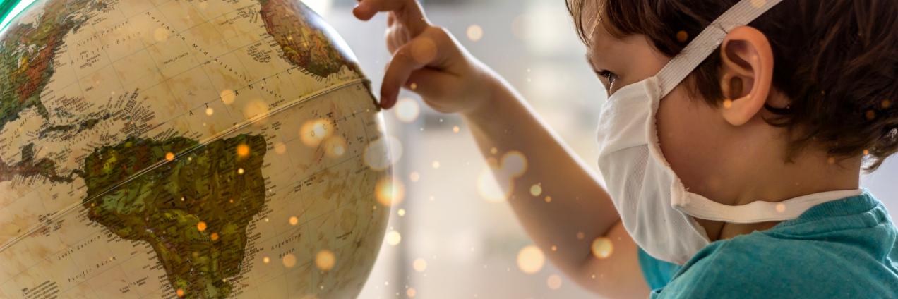 foto de un niño con mascarilla tocando un globo terráqueo