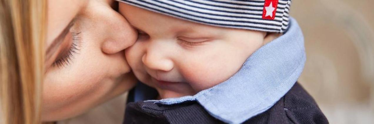Las caras de una madre besando en la mejilla a su hijo sonriente