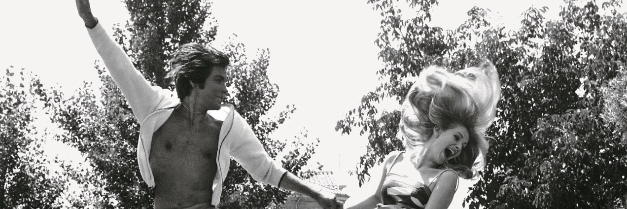 imagen de una pareja en un jardín saltando en el aire mientras se da de la mano