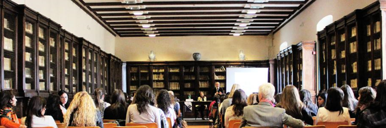 Sala de conferencias con docente y público asistente sentado