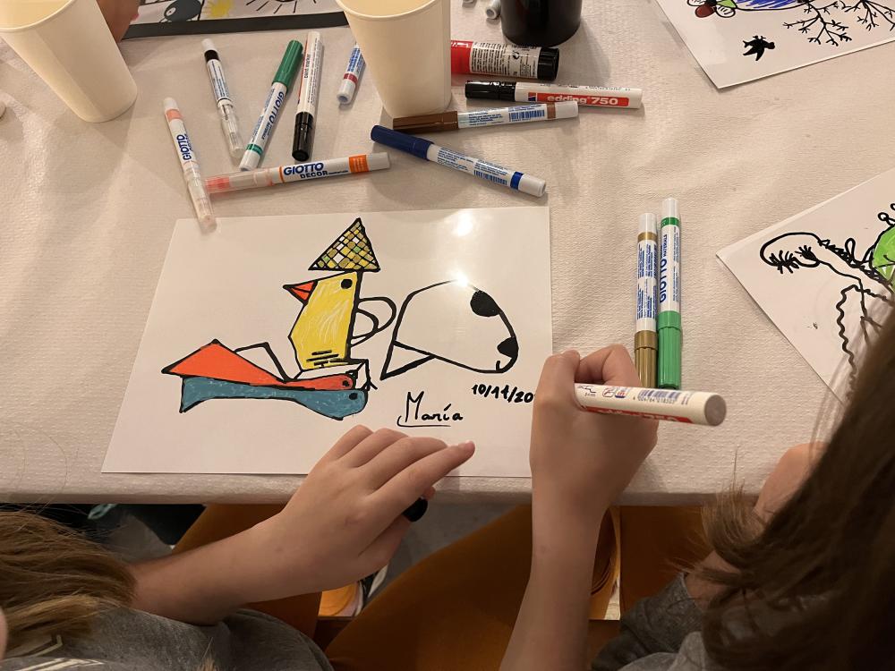 Las manos de una niña pintando sobre una mesa
