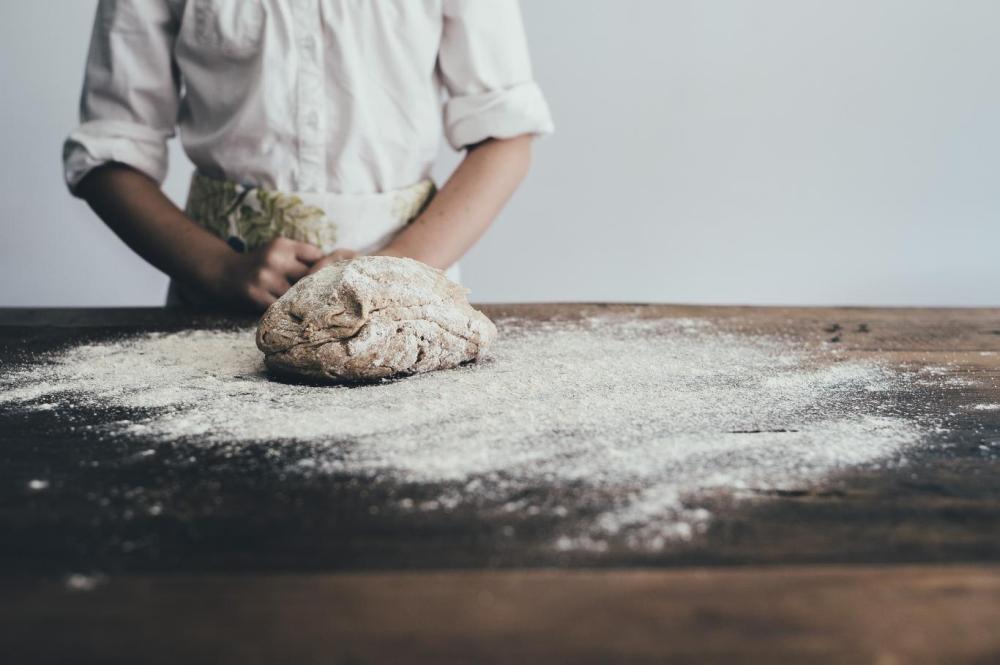 Persona amasando masa de pan en una mesa de madera