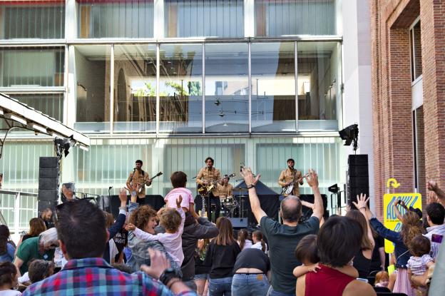 Imagren de grupo de música tocando sobre escenario mientras el público levanta las manos
