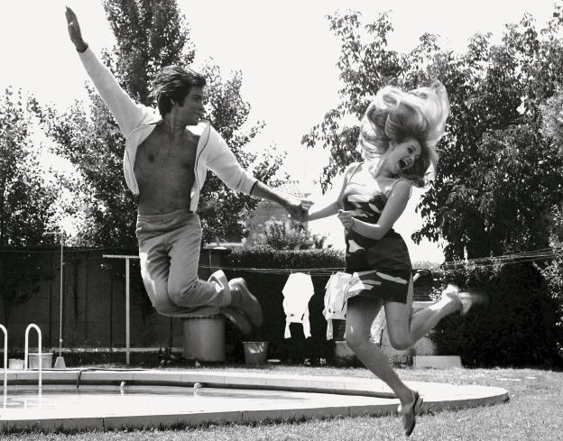 imagen de una pareja en un jardín saltando en el aire mientras se da de la mano