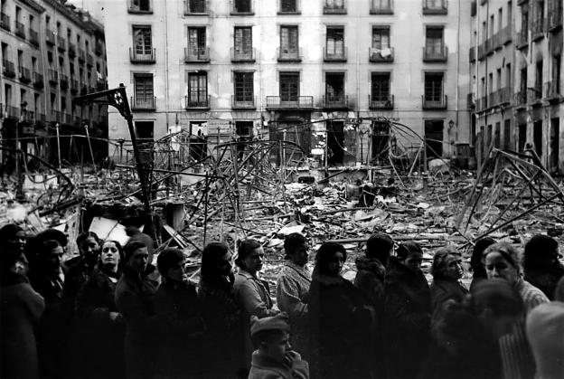 Imagen de grupo de mujeres pasando frente a una plaza bombardeada