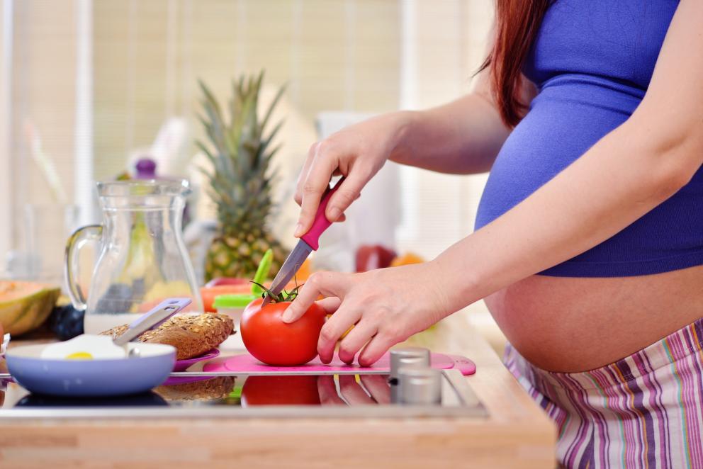 Embarazada cortando un alimento en la cocina