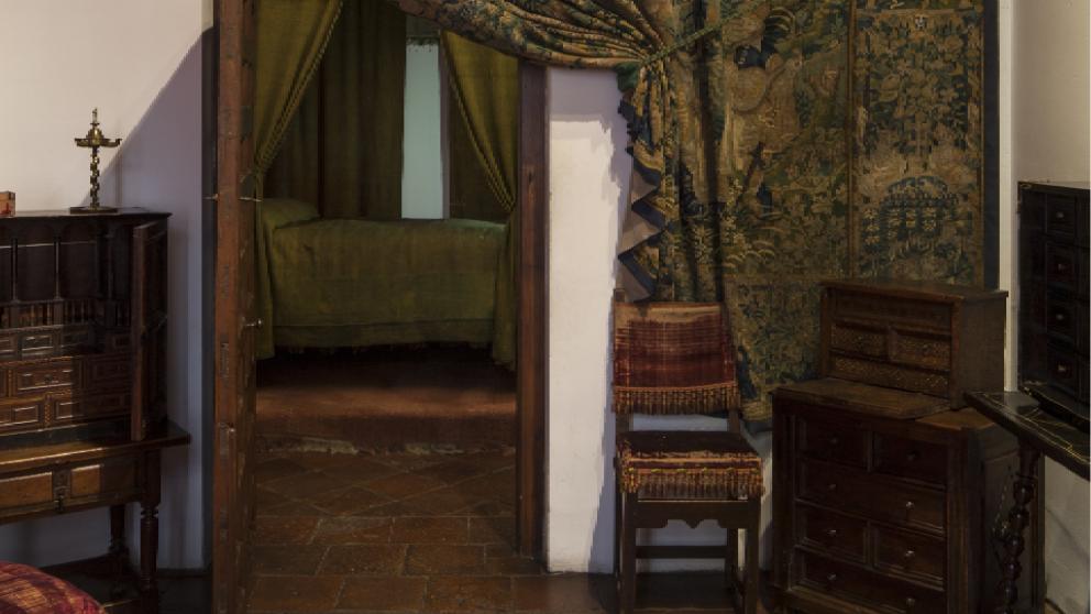 Entrada a un dormitorio antiguo con dosel y colcha en verde