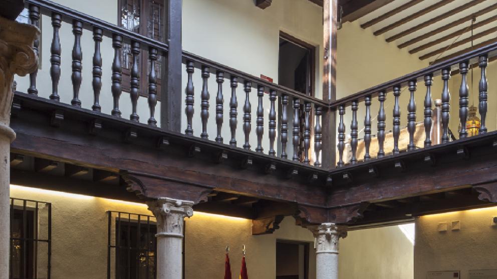 Vista de un patio interior con dos alturas y una barandilla de maderar en la planta superior