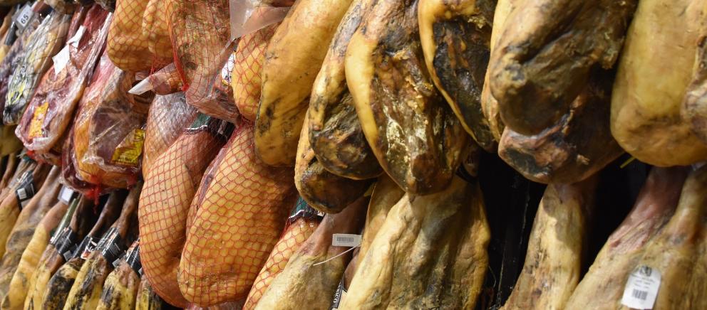 Primer plano de unos jamones colgados en almacén