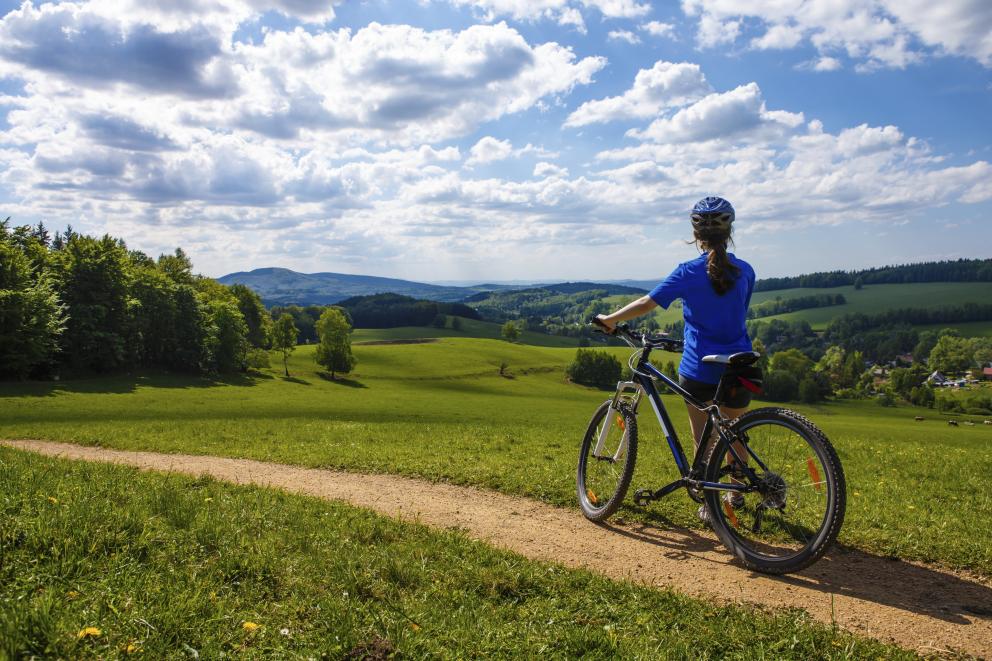 Ciclista de espaldas contemplando un paisaje verde