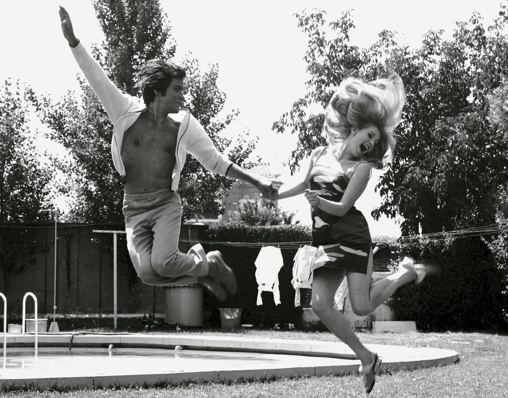 imagen de una pareja en un jardín saltando en el aire mientras se da de la mano