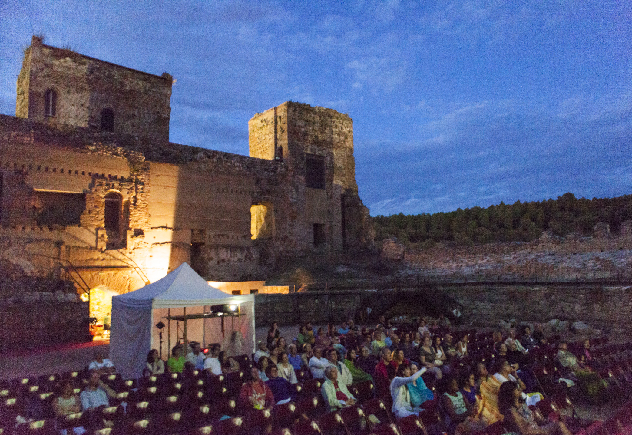 Público en un cine de verano con un castillo de fondo